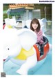 A young girl riding an elephant ride at an amusement park.