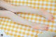 A woman's legs are laying on a yellow and white checkered blanket.