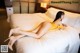 A woman in a yellow dress laying on a bed.