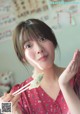 A woman holding chopsticks in front of her face.