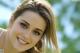 A beautiful young woman with long brown hair smiling.